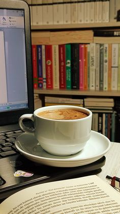 a cup of coffee sitting on top of a saucer next to an open book