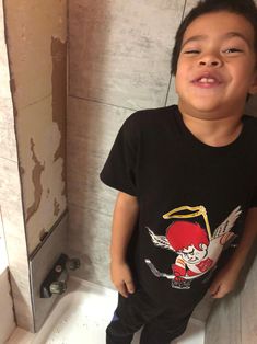 a young boy standing in the corner of a bathroom