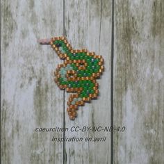 the beaded bird is hanging on the wooden fence