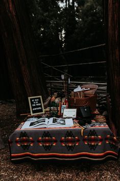 an outdoor picnic table with books and pictures on it in the woods next to some trees