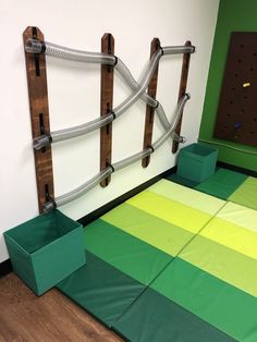 an indoor play area with green and yellow squares on the floor next to a wooden fence