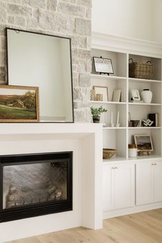 a fireplace with white shelves and a mirror on it's wall above the fire place