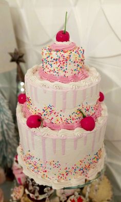 a three tiered cake with sprinkles and cherries