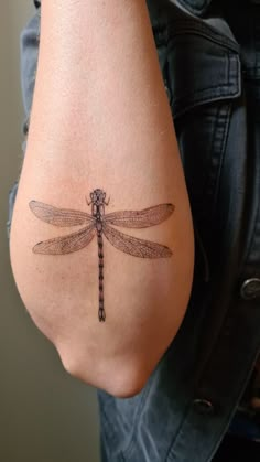 a woman's arm with a tattoo on it that has a dragonfly on it