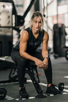 a woman squatting down on a stationary exercise bike in a crossfit gym