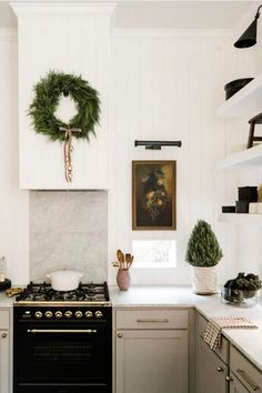 a kitchen with white cabinets and a wreath hanging on the wall above the stove top