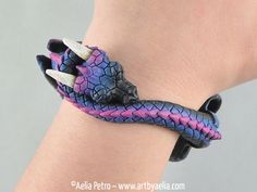 a purple and blue dragon bracelet on someone's wrist with horns attached to it