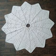 a white crocheted doily sitting on top of a wooden floor