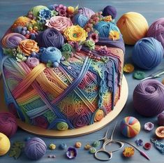 there is a cake decorated with yarn and crochet hooks on the table next to it