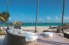 an outdoor seating area on the beach with palm trees