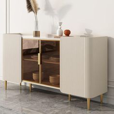 a white and gold sideboard with some vases on the shelf next to it