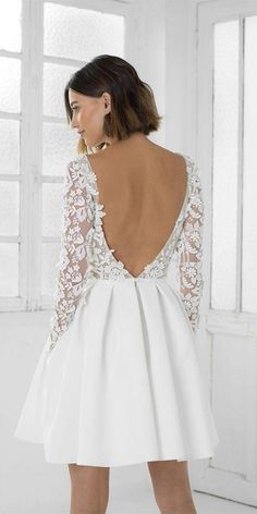 the back of a woman's white dress with long sleeves and lace on it