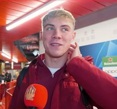 a young man is talking to the camera while holding his ear up in front of him