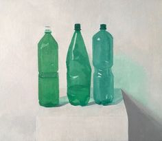 three green bottles sitting on top of a white block