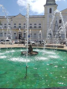 a fountain in front of a large building with water spouting from it's sides