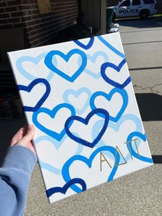 someone holding up a painting with blue hearts on it