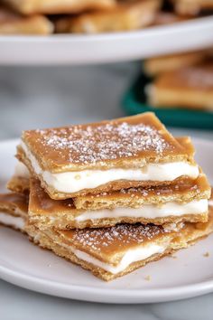 three pieces of dessert sitting on top of a white plate next to another plate filled with pancakes