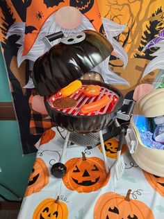 a table topped with lots of halloween treats and candy in a bowl on top of it