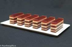 several pieces of cake sitting on top of a white plate with red and brown squares