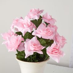 a white vase filled with pink flowers on top of a table