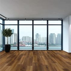 an empty room with wooden floors and large windows overlooking the cityscape in the distance