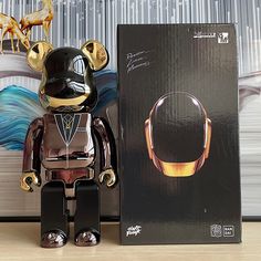 a black and gold bear next to a box with earphones on it's head