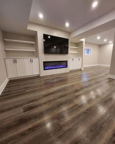 an empty living room with wood flooring and built - in entertainment center on the far wall