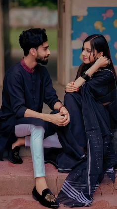 a man and woman sitting next to each other on the steps in front of a building