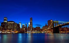 the city skyline is lit up at night with lights reflecting on the water and skyscrapers in the background