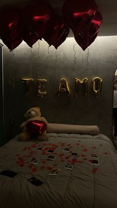 a teddy bear sitting on top of a bed in a room with balloons and streamers