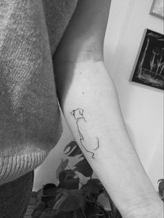 a black and white photo of a person's arm with a cat tattoo on it