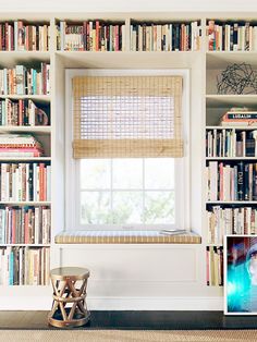 a window seat in front of a bookshelf filled with books