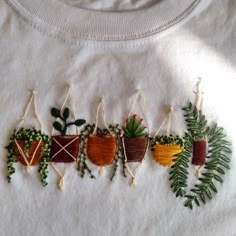 an embroidered t - shirt with potted plants hanging from it's front and sides