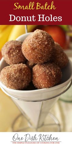 small batch donut holes in a white bowl on a table with bananas and apples