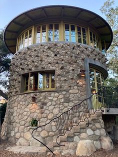 a round stone building with stairs leading up to the second floor and windows on each side