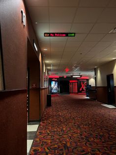 an empty hallway with red and yellow carpeting in front of the exit to another room