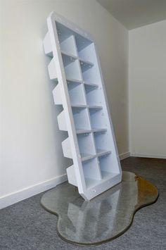 a large white book shelf sitting on top of a gray floor next to a wall