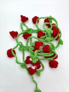 crocheted red and green flowers on a white surface