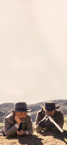 two men sitting on the ground wearing hats