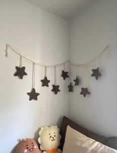 a teddy bear sitting on top of a bed next to a stuffed star garland hanging from the ceiling