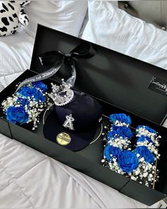 three blue roses in a black box on a bed