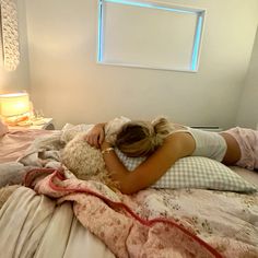 a woman laying in bed with her head on a teddy bear