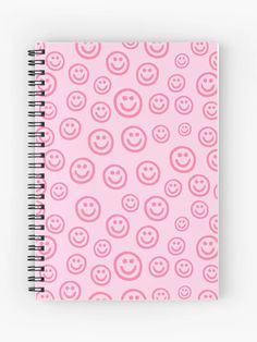 a spiral notebook with pink smiley faces on the front and bottom, all over it