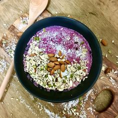 a bowl filled with food sitting on top of a wooden table next to a spoon