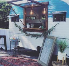 an old camper is decorated with greenery and hanging from the ceiling for display