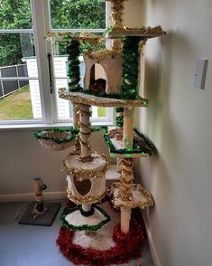 a cat tree in the corner of a room with christmas decorations and lights on it