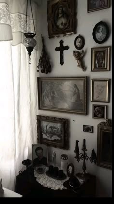 there are many framed pictures on the wall in this room with white drapes and curtains