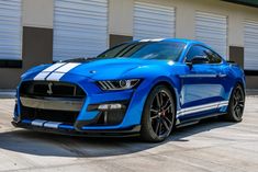 a blue mustang parked in front of a building