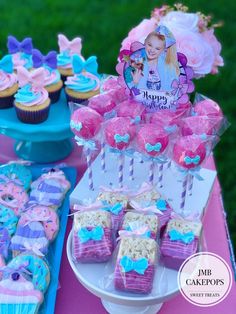 a table topped with cupcakes and cakes covered in frosting