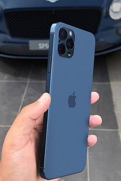 a person holding an iphone in front of a blue car